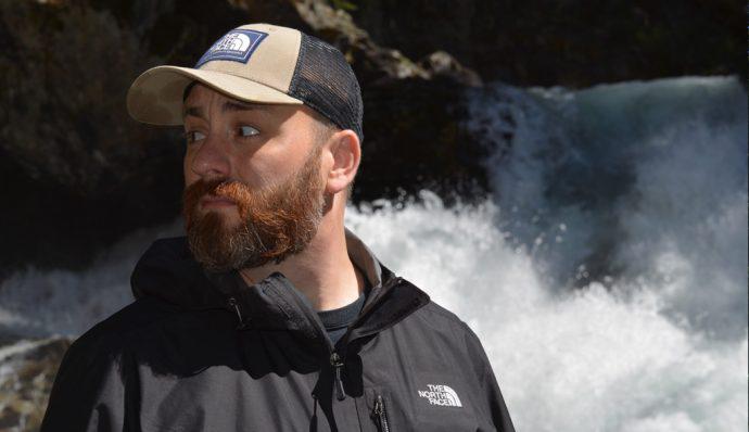 Author Jon Lewis standing in front of a waterfall