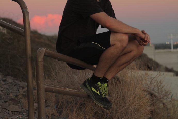 Man sits on fence while wearing Brooks Ghost 9 GTX® Shoes