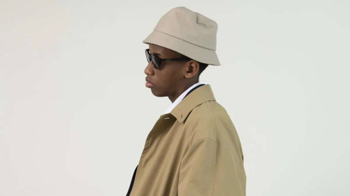 African American Man in tan trench coat, tan bucket hat, and sunglasses