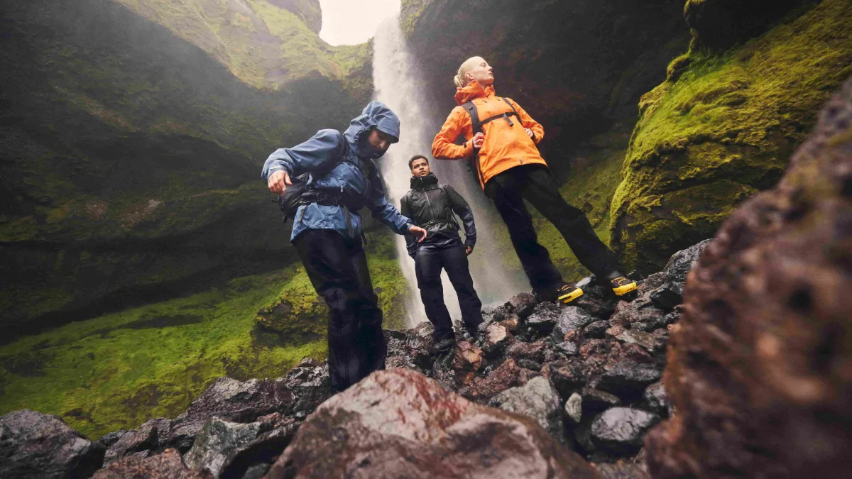 Three hikers under a waterfall, wearing GORE-TEX Gear