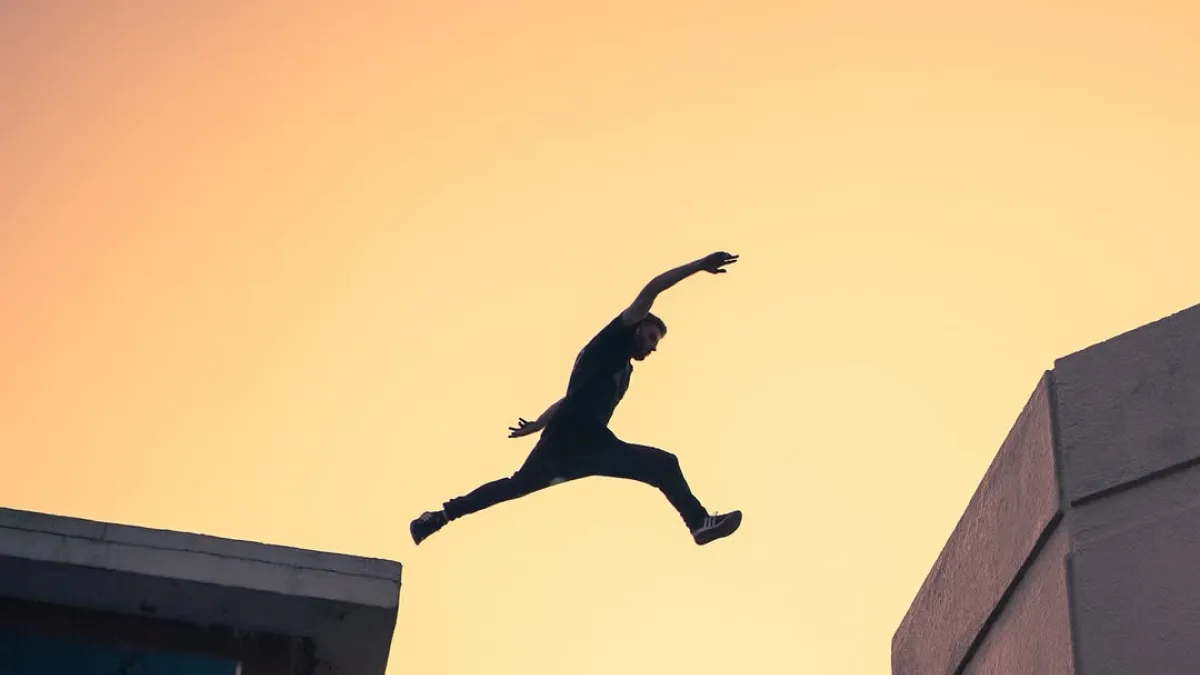 Toby Segar jumping across building at sunset
