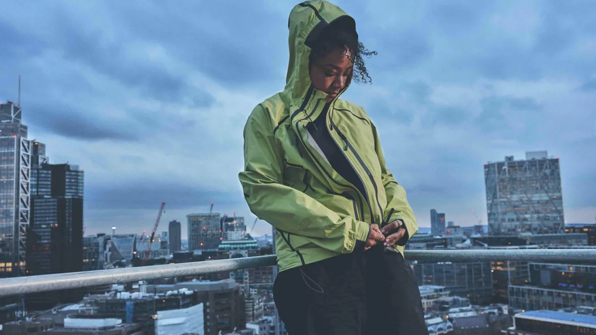 Woman zipping up a GORE-TEX Jacket, standing on a city rooftop
