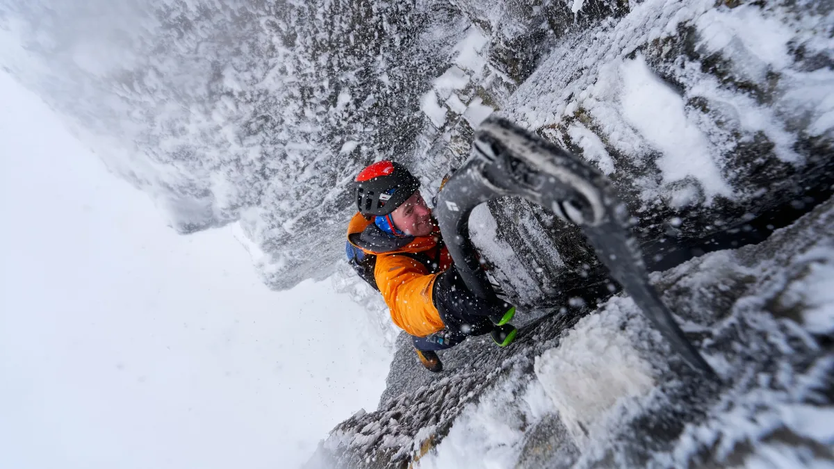 Man rock climbing in extreme snowy conditions
