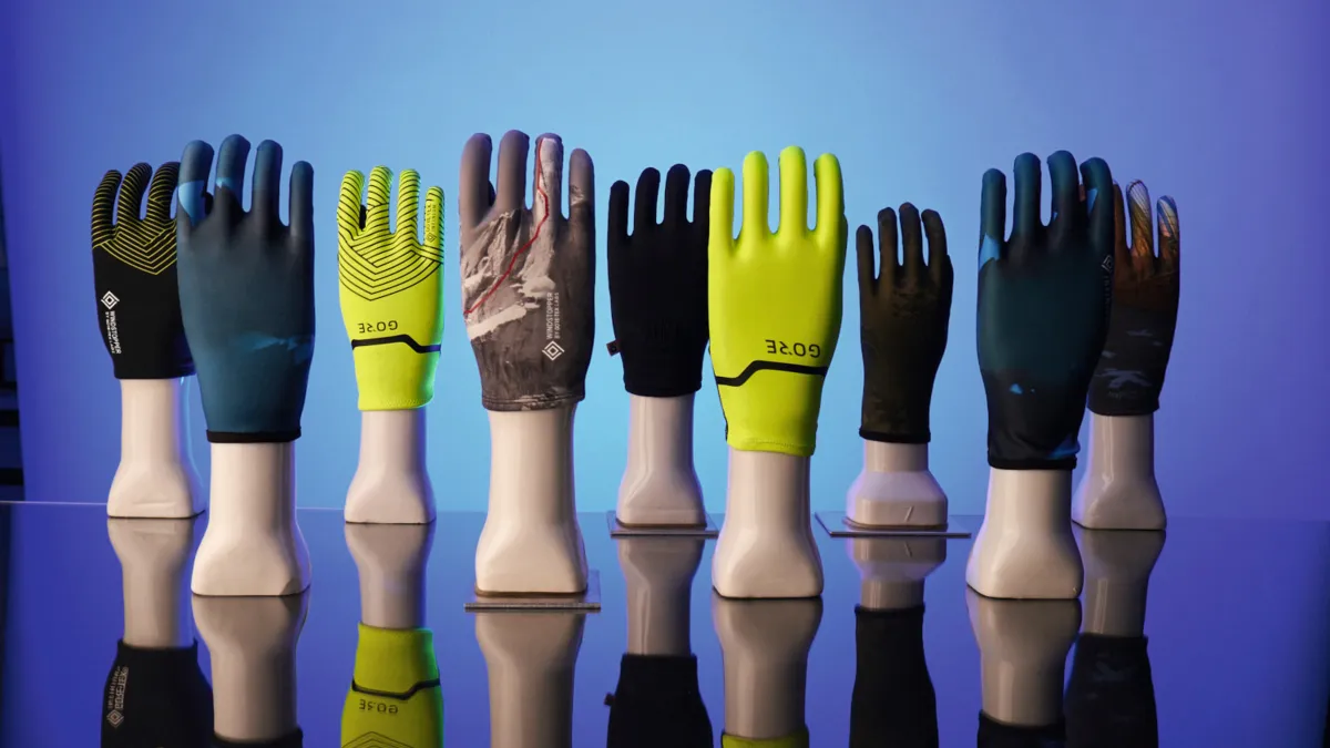 Line of GORE-TEX Gloves on stands against a blue background